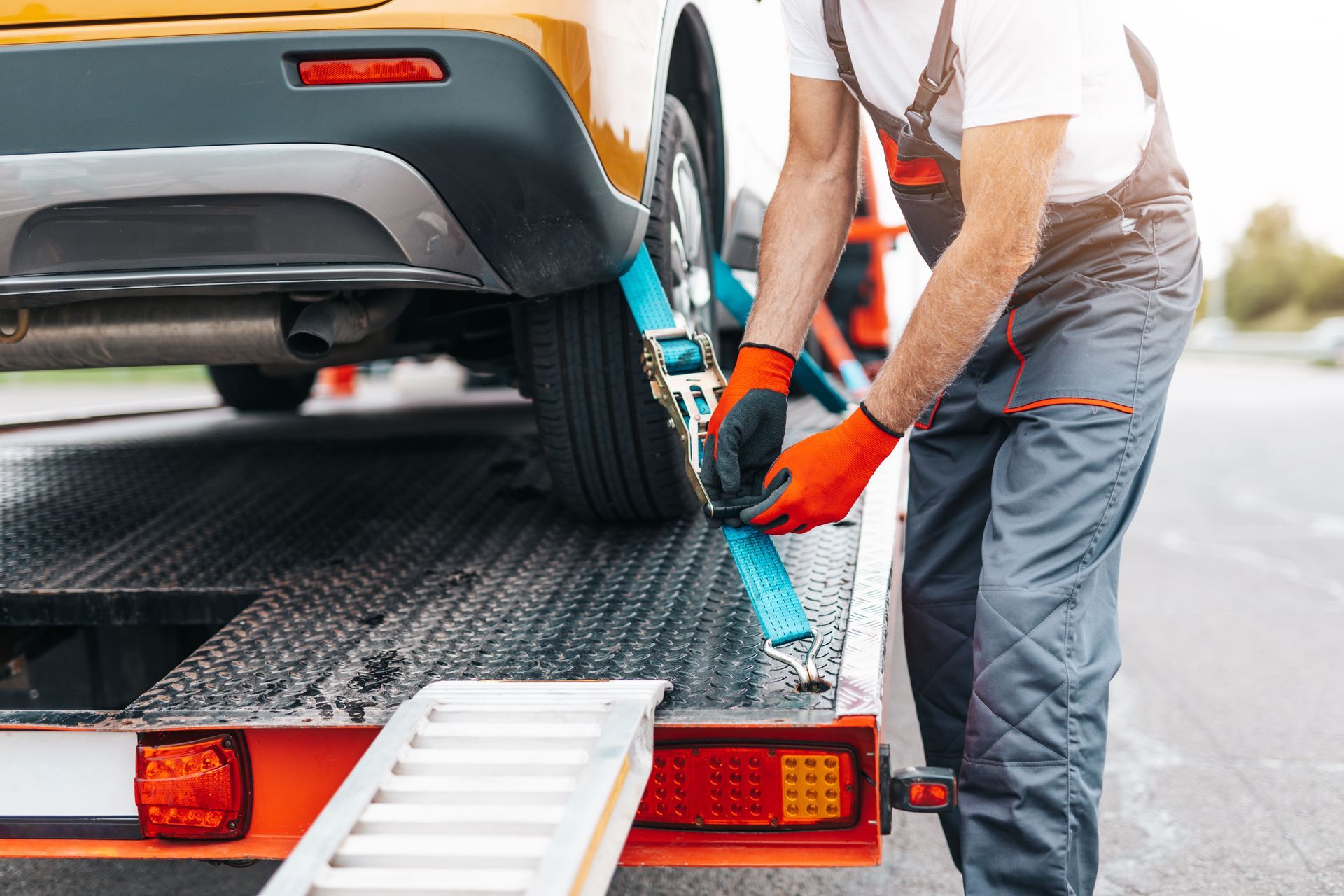 Close-up of technician loading vehicle onto tow truck for 24 hour towing service support.