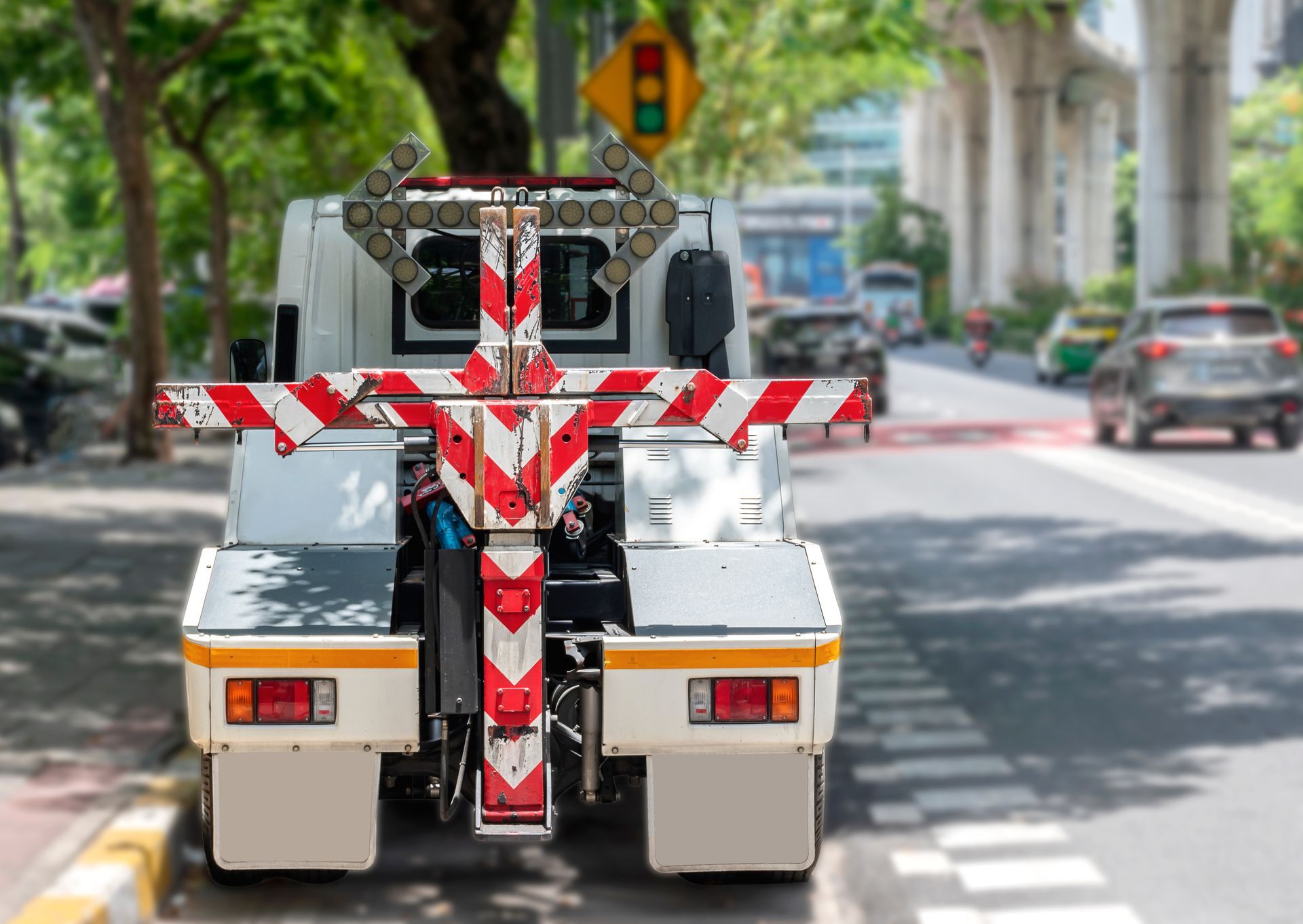 24 hour towing truck with red reflective lift parked on city street in daylight.
