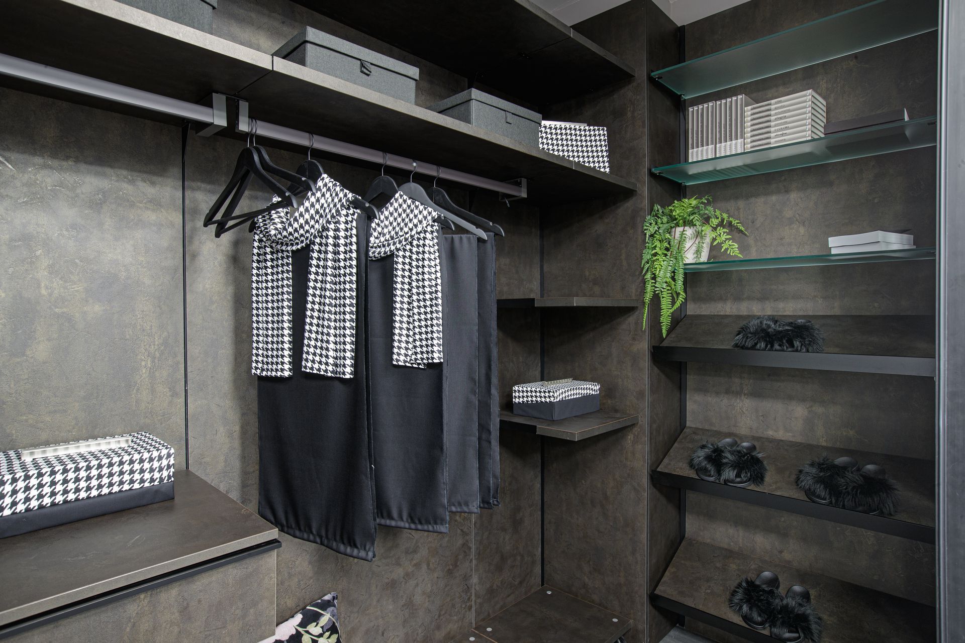 Armadio buio con vestiti appesi, scaffali, scatole e ripiani in vetro.