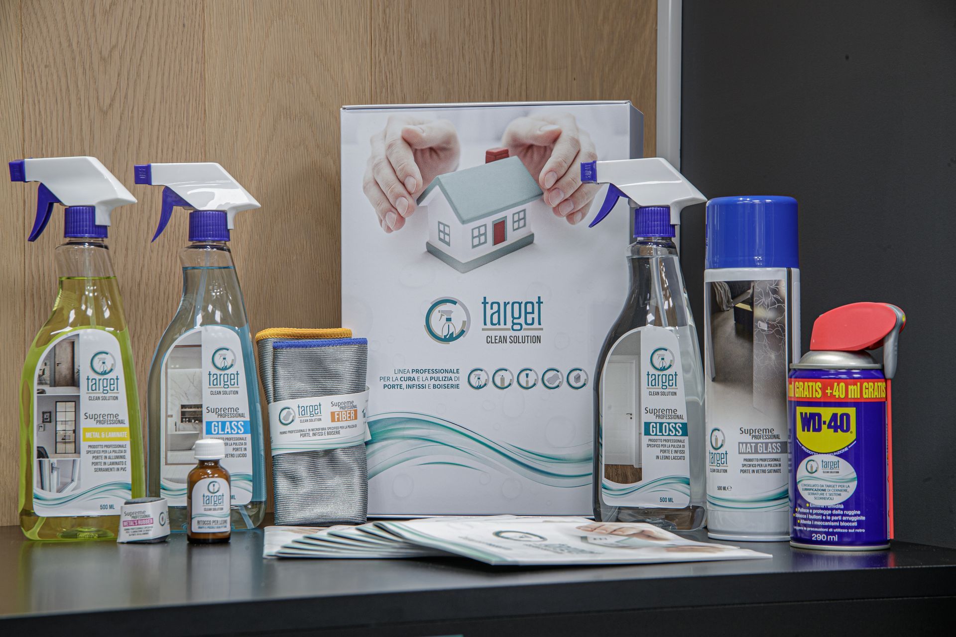 Prodotti per la pulizia su uno scaffale, tra cui flaconi spray e WD-40, con un logo raffigurante una casa.