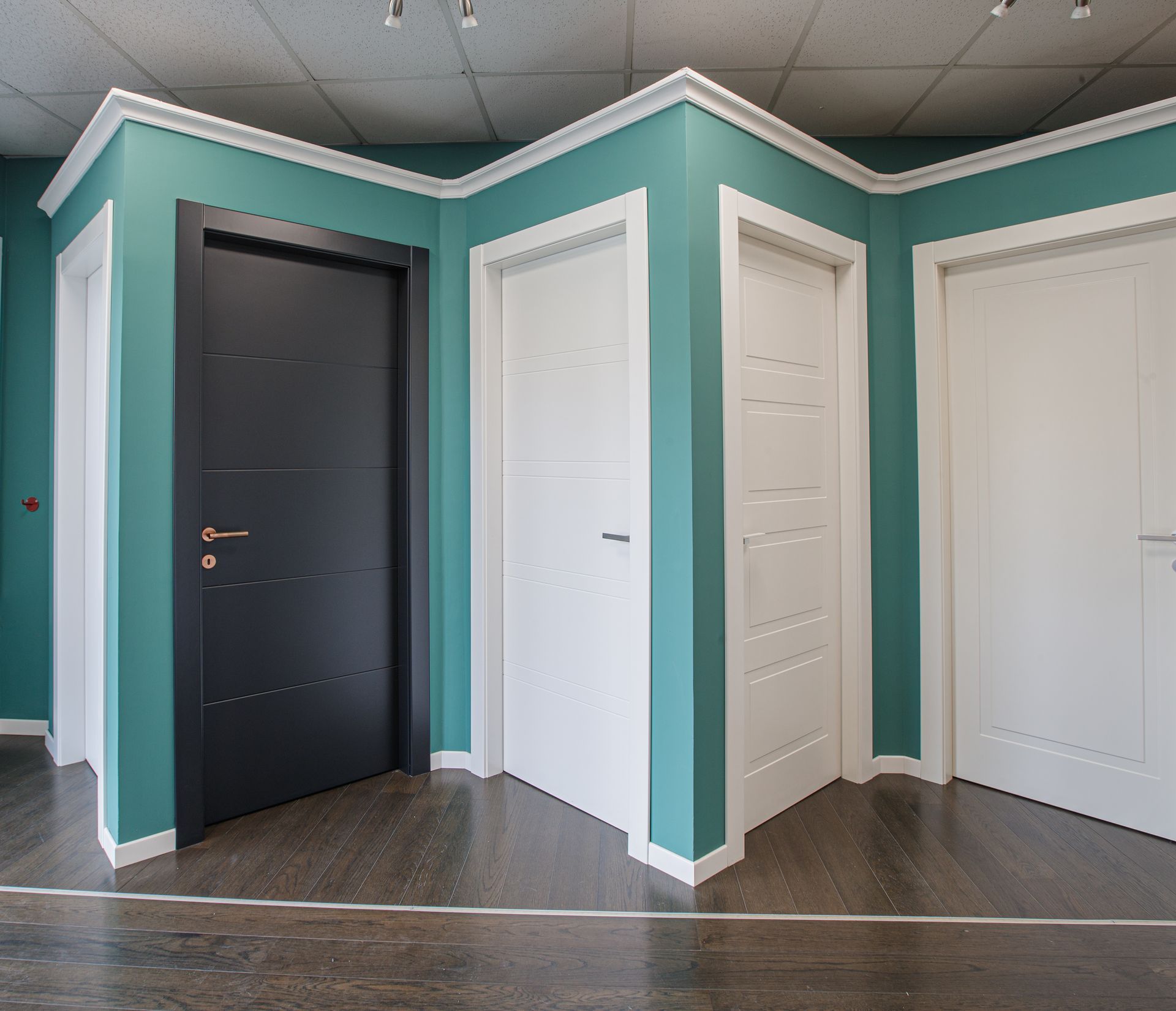 Porte esposte: nere, due bianche, pareti turchesi, pavimento in legno scuro, finiture bianche.