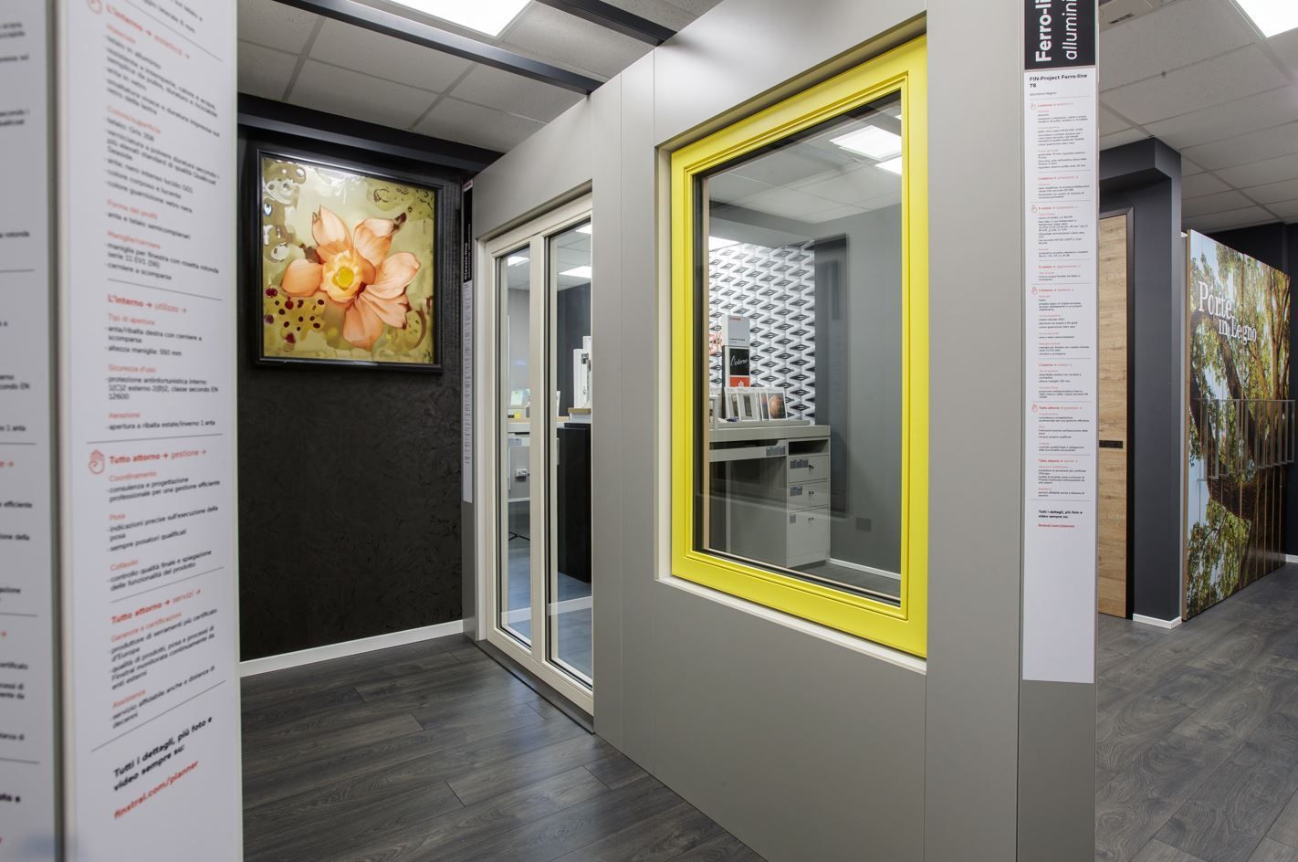 Interno di uno showroom con vetrine e porte espositive; telaio della finestra giallo, porta scorrevole.