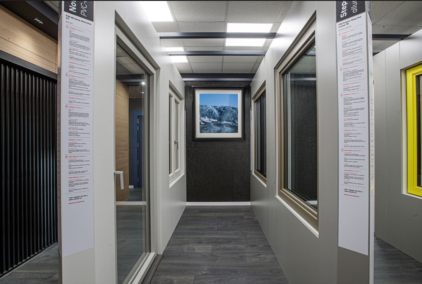 Corridoio interno con vetrine e porte decorate con una scena di montagna.