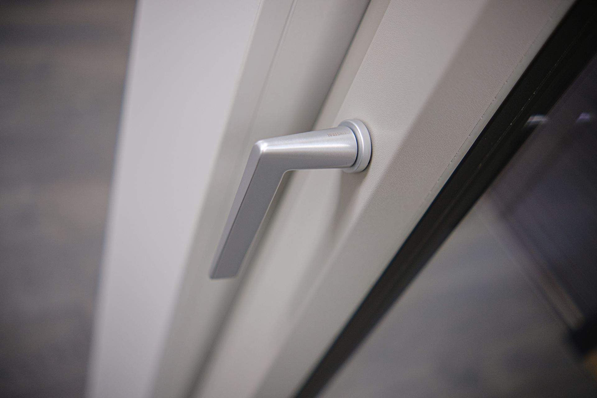 Maniglia per finestra argentata su telaio bianco, pronta per essere aperta.