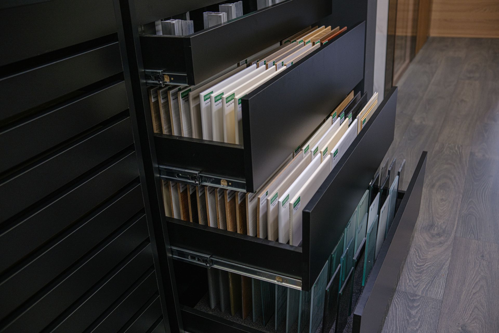 Mobiletto nero con cassetti estraibili contenenti campioni di colori di vari materiali, tutti ordinati.