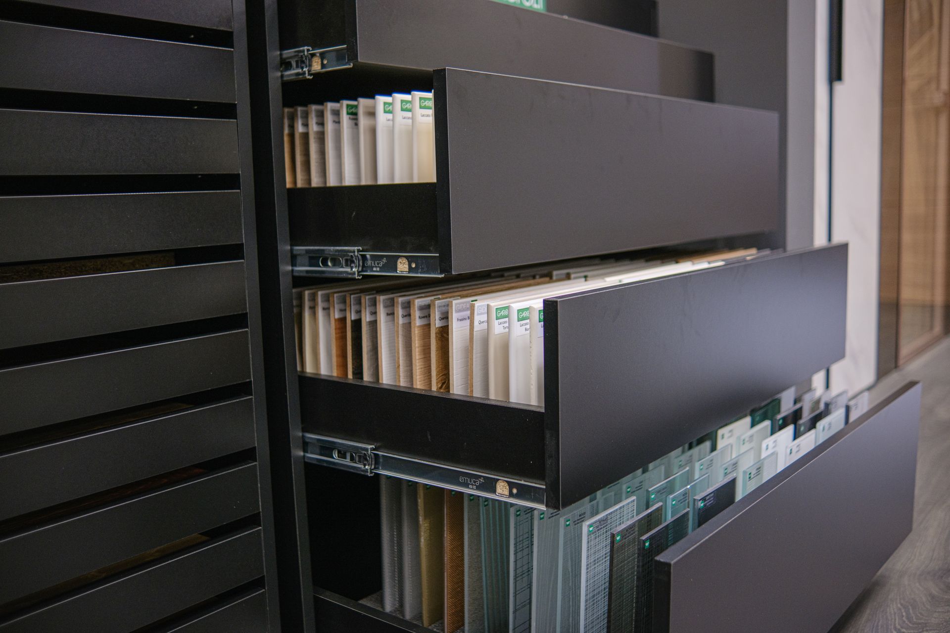 Vetrina nera con cassetti estraibili, piena di campioni di materiali.