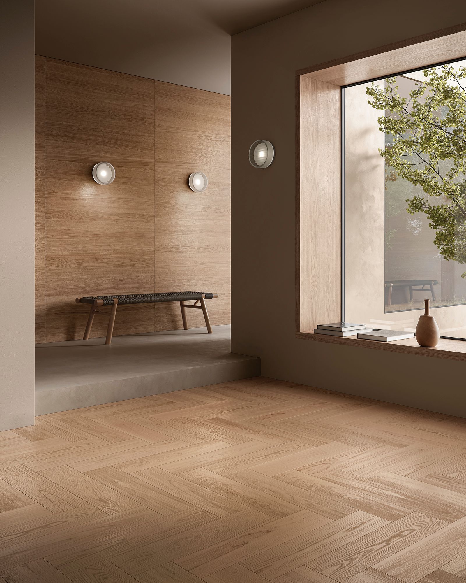 Un interno luminoso con pavimenti in legno. Una panca è appoggiata a una parete strutturata con illuminazione a parete, e una finestra mostra il verde della vegetazione esterna.