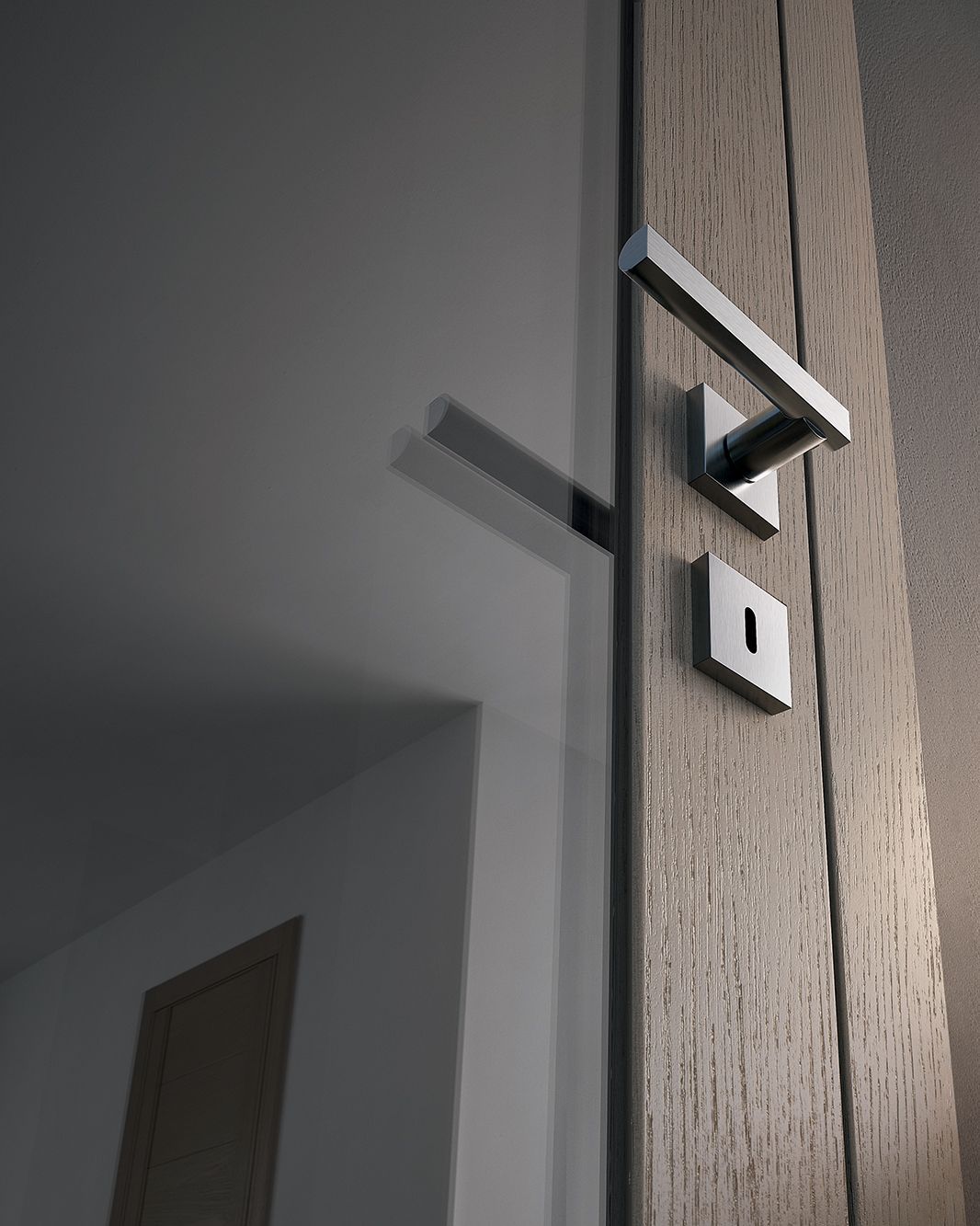 Maniglia della porta su uno stipite in legno, con una serratura sotto la maniglia, che riflette un interno bianco.