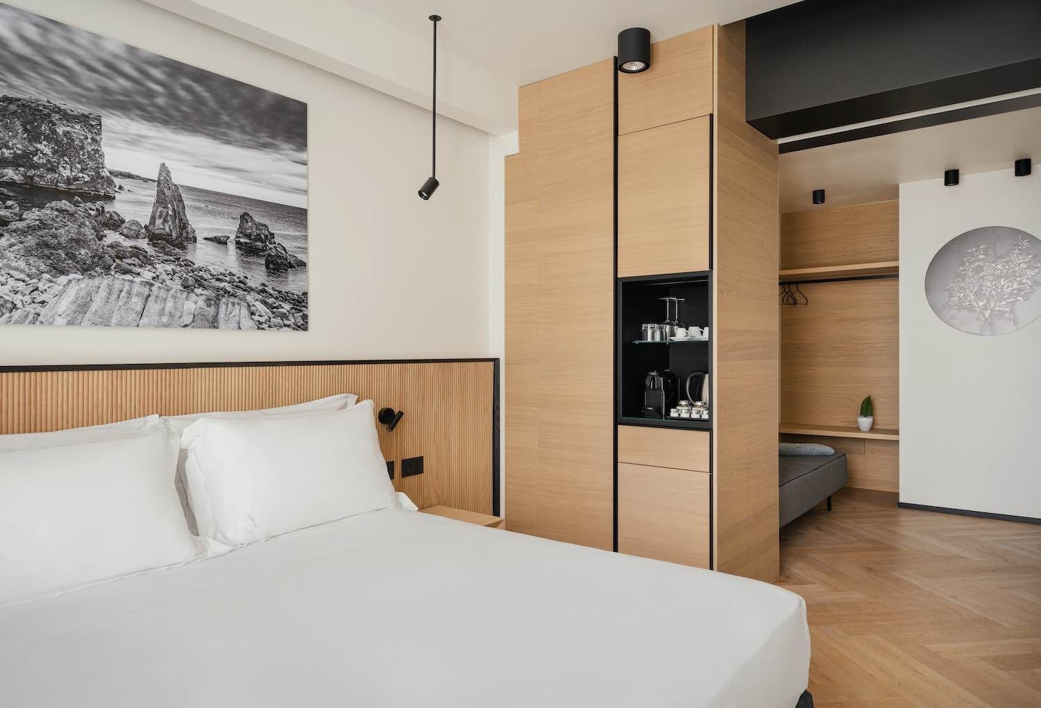 Interno della camera da letto con letto, spazio contenitore incorporato, quadri raffiguranti paesaggi marini.