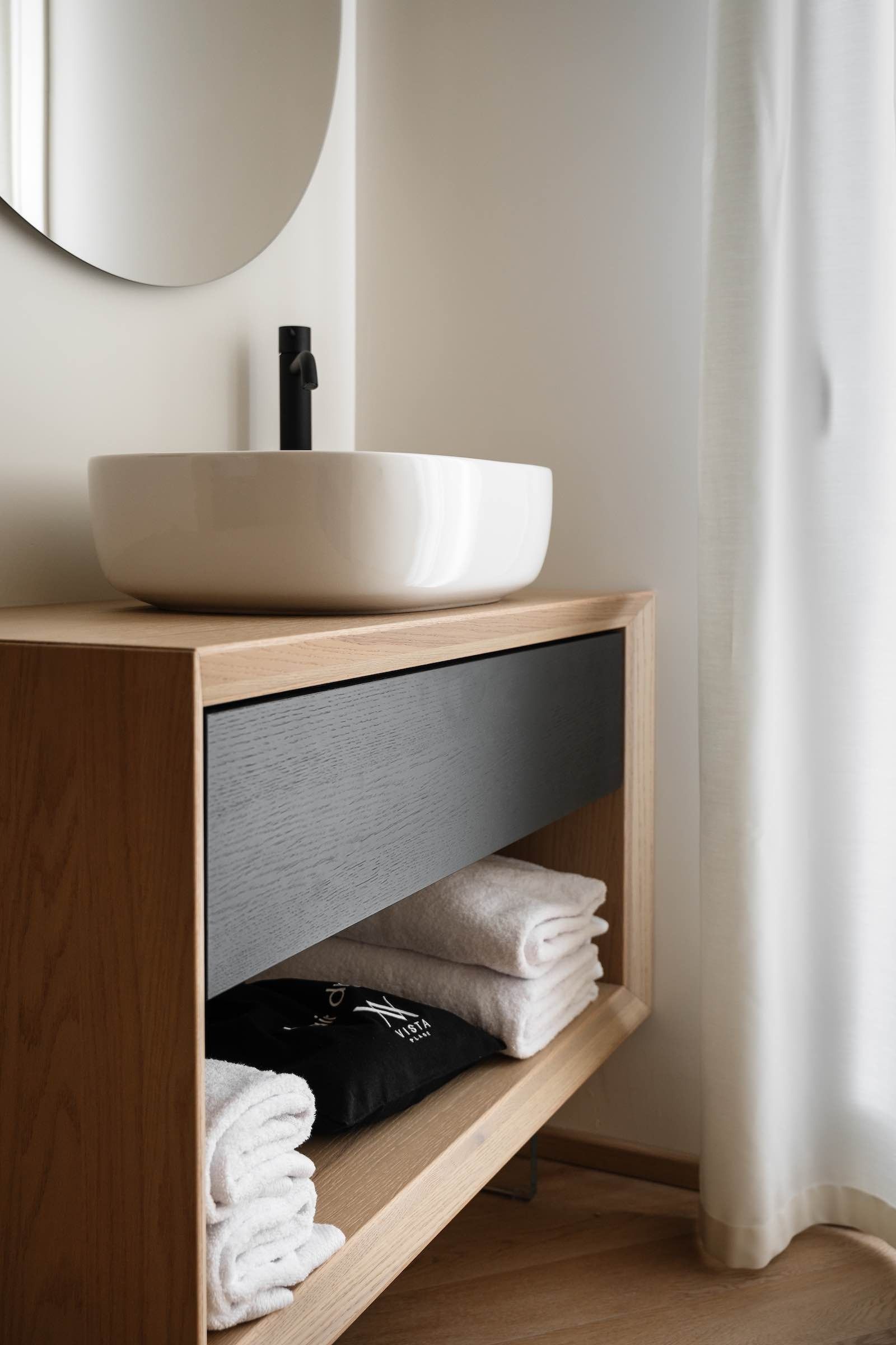 Mobiletto per il bagno con lavandino rotondo, mobiletto in legno e asciugamani.