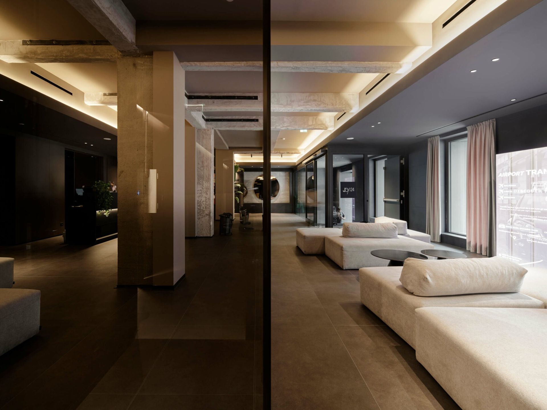 Un interno moderno con vista divisa, un lungo divano beige, ampie finestre e un divisorio a specchio.