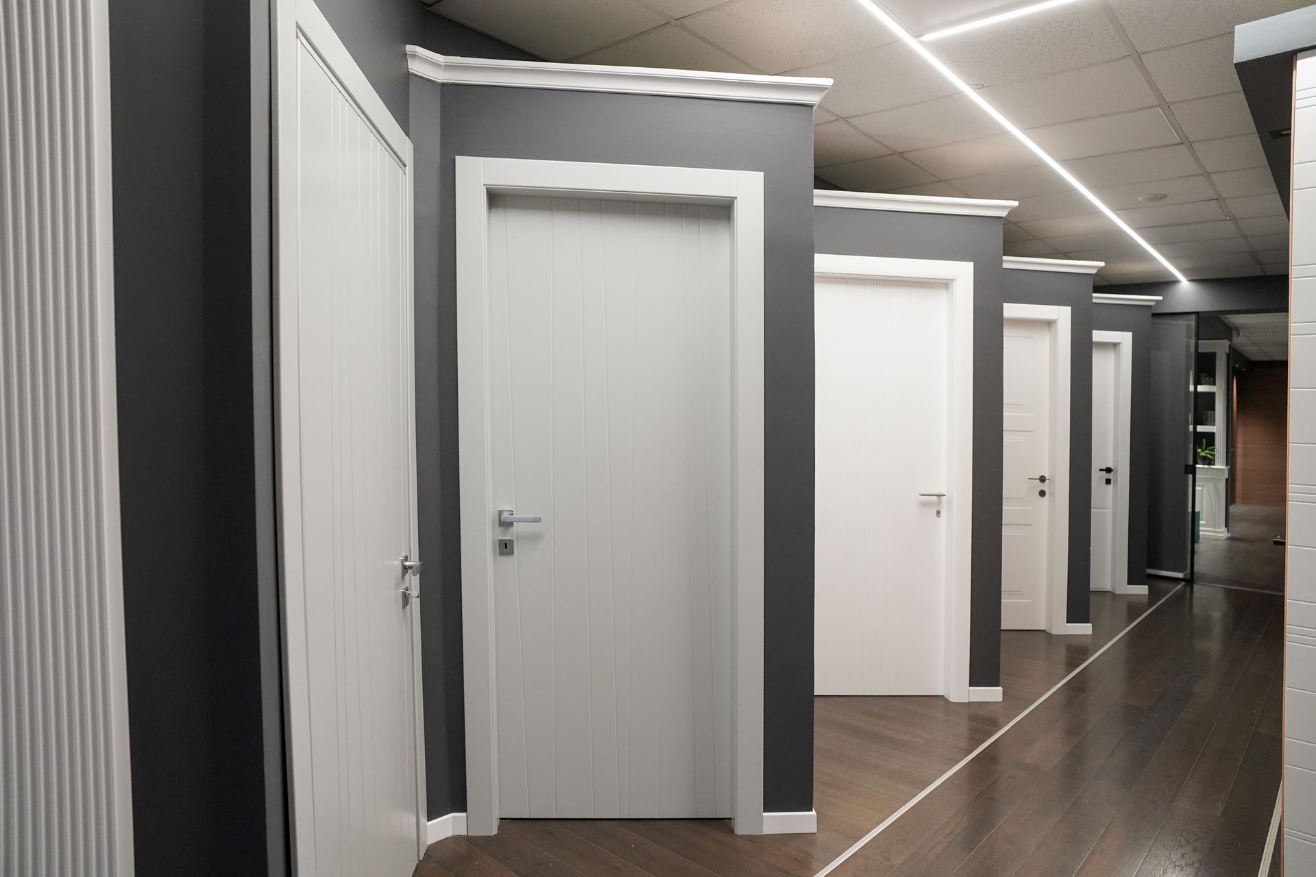 Porte bianche in fila, contro pareti grigie, all'interno di un edificio.