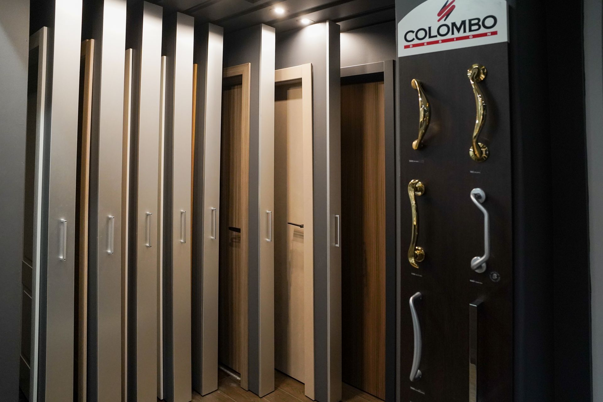 Campioni di porte e ferramenta esposti in uno showroom, con vari stili di porte, colori e opzioni di maniglie.