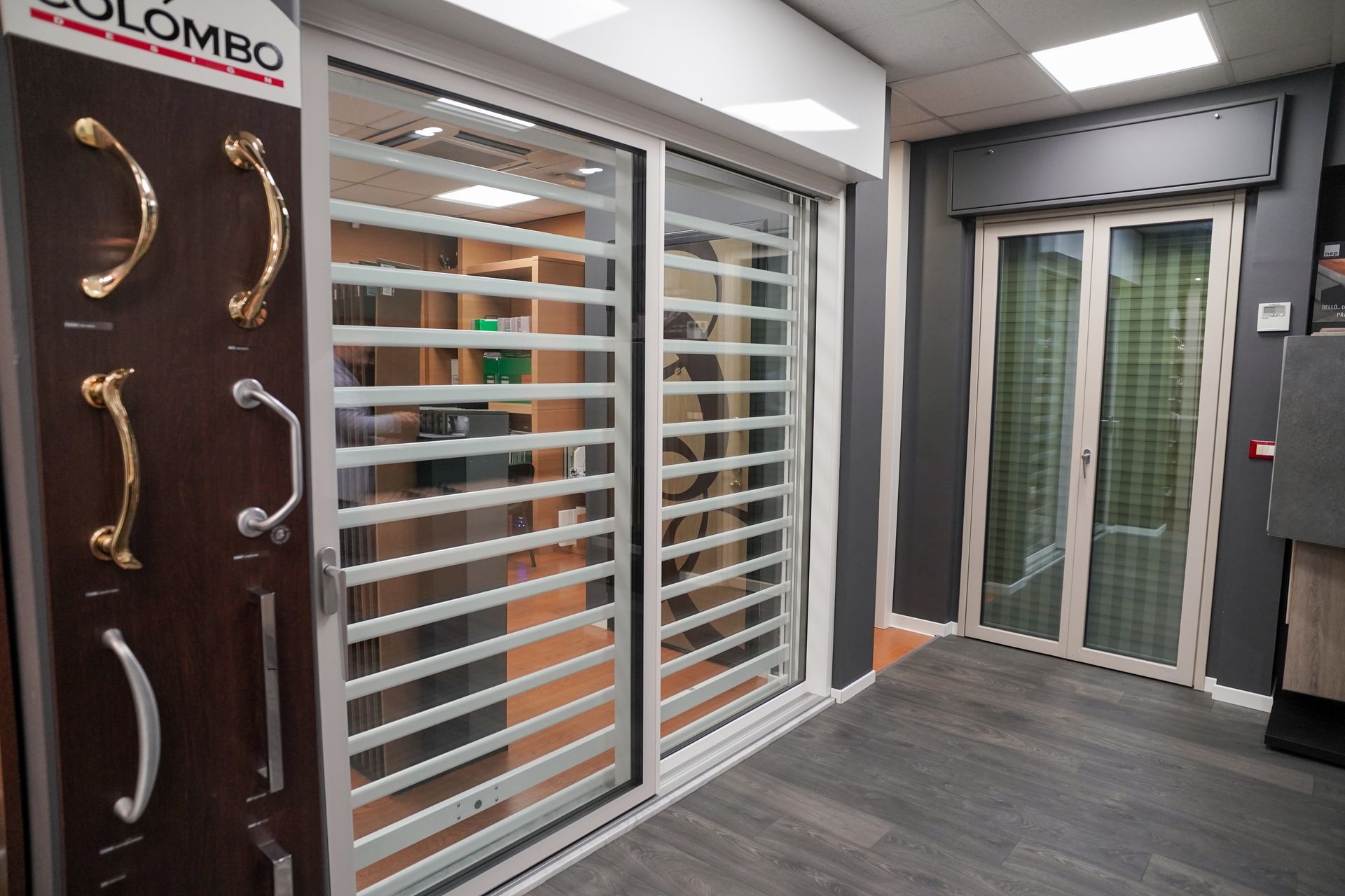 Espositore con porte scorrevoli in vetro e maniglie. Combinazione di colori grigio e bianco.