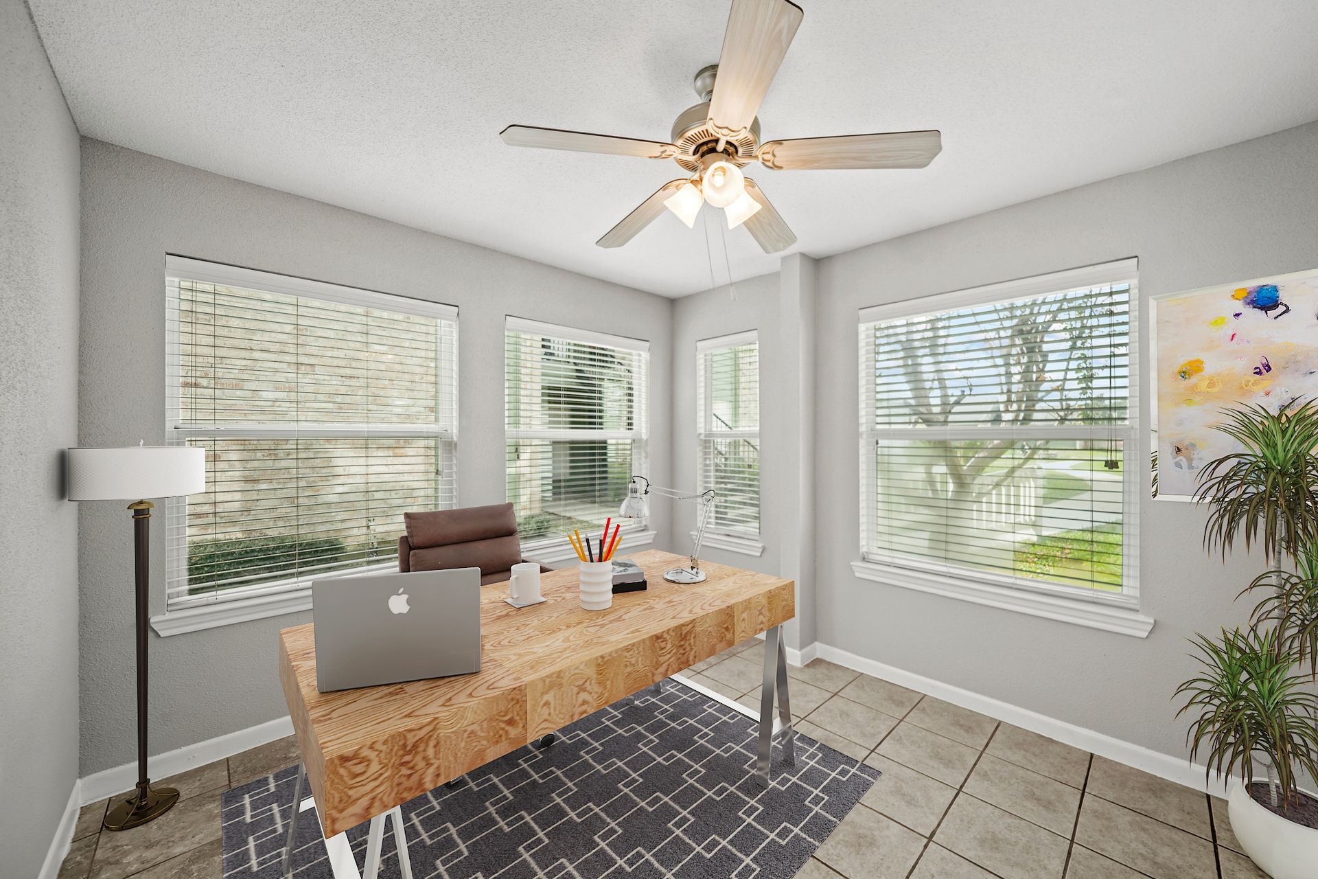 A home office with a desk , chair , laptop and ceiling fan.