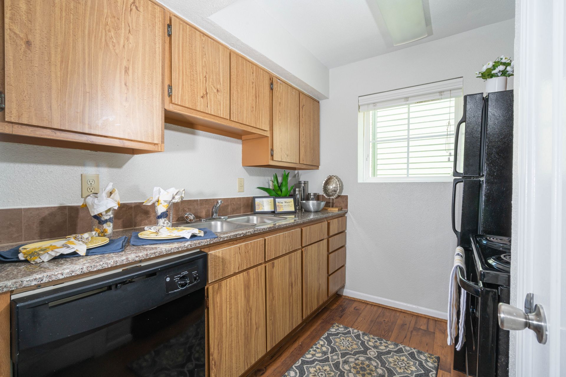 A kitchen with wooden cabinets , a black refrigerator and a black dishwasher.