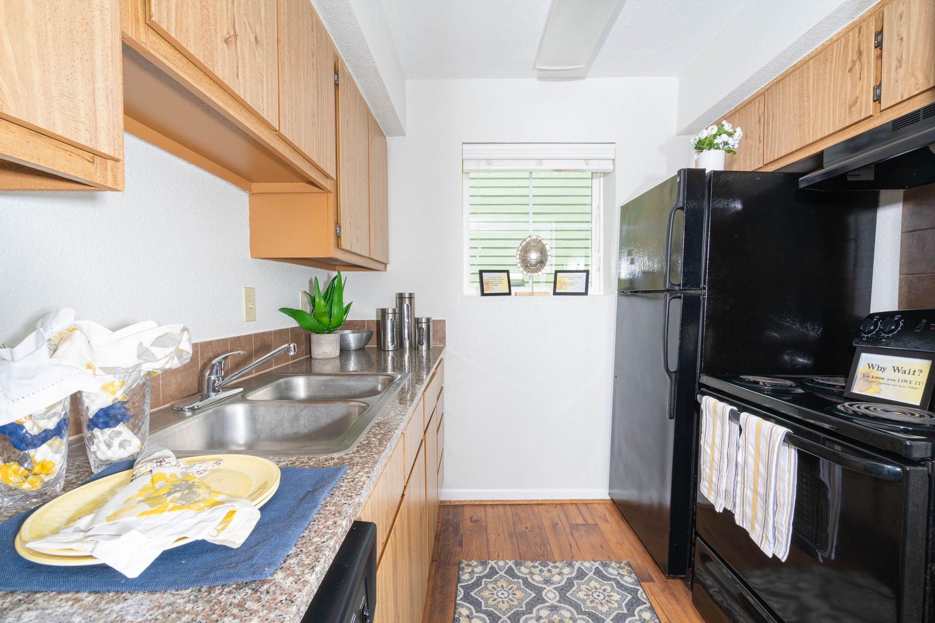A kitchen with a sink , stove , refrigerator and window.