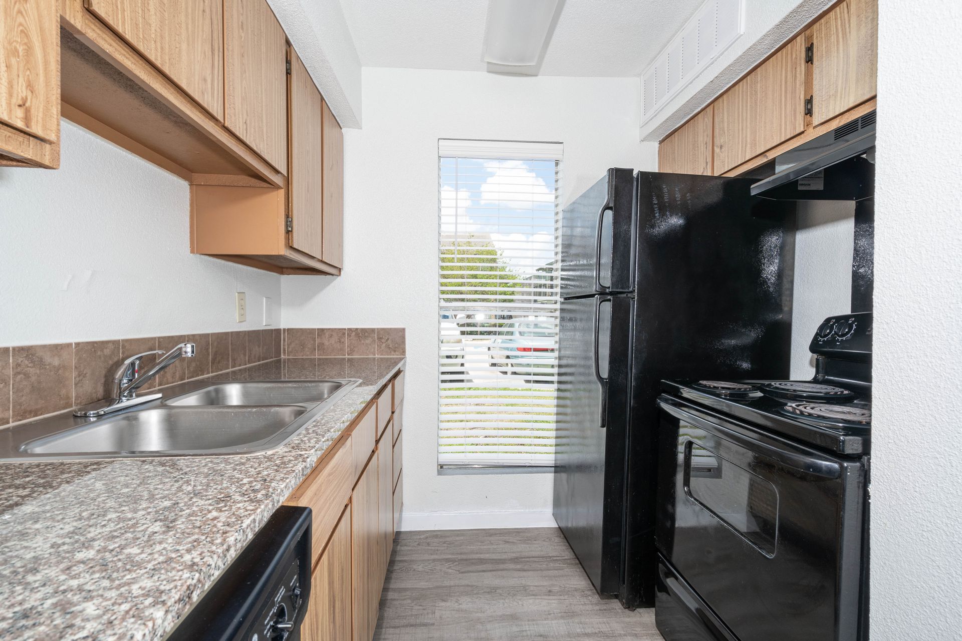 A kitchen with a black refrigerator stove and sink
