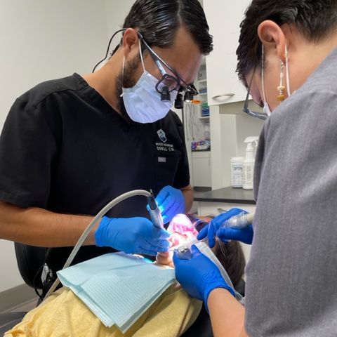 dr sisneros working with a patient with the help of a dental assistant