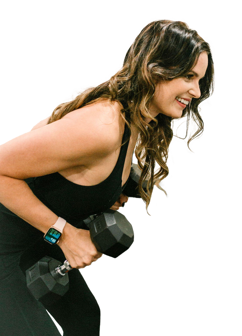 A woman in a black tank top is holding a dumbbell and smiling.