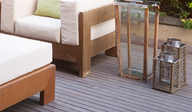 A wooden deck with chairs , a table and lanterns on it.