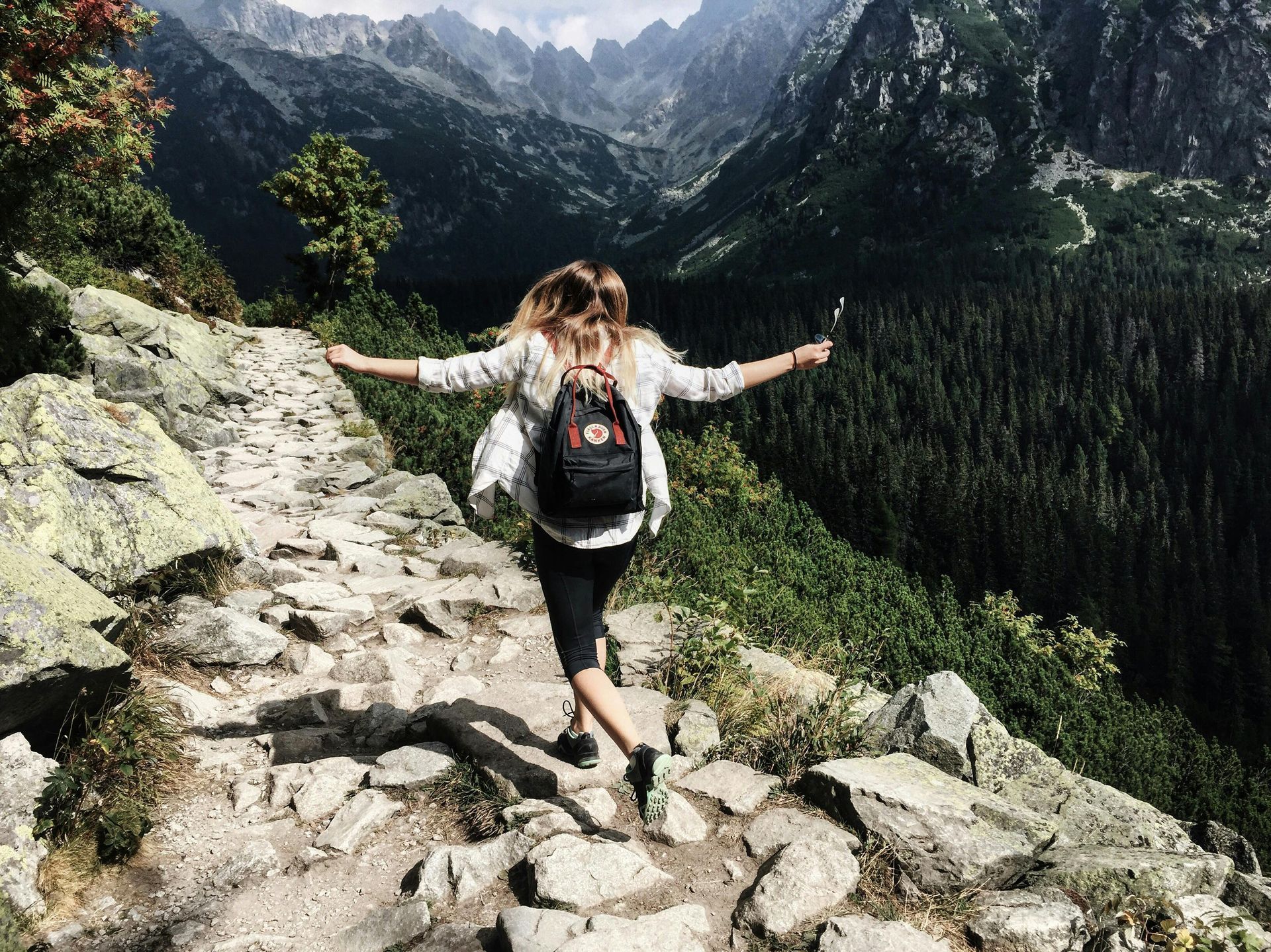 Woman with a backpack walking on a rocky mountain path, without mountain views in the background