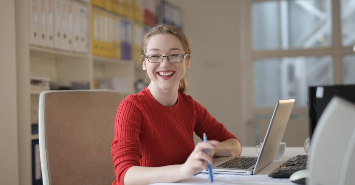 Smiling girl sitting at a desk with a laptop.