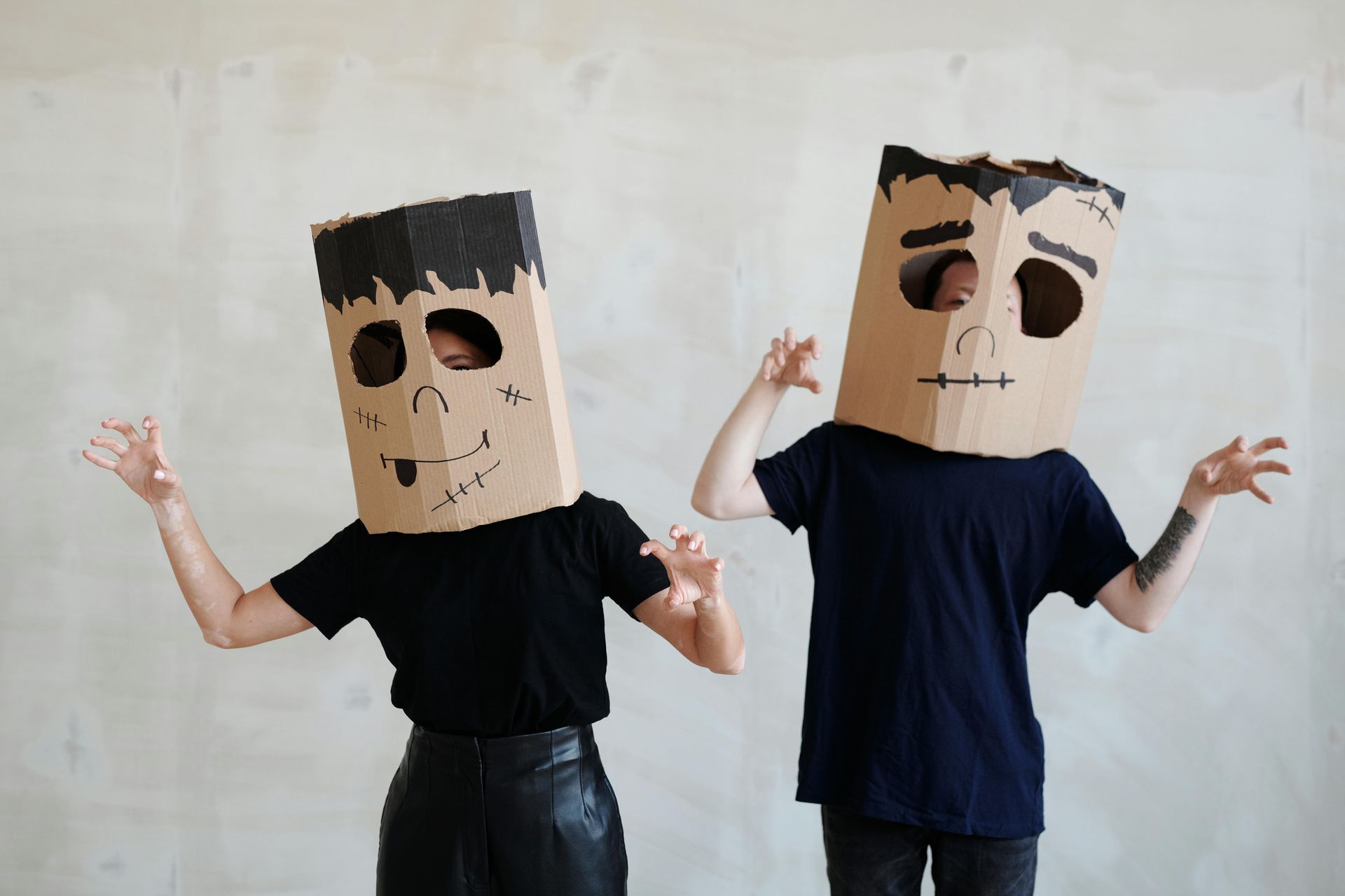 Man and woman dressed in black with cardboard boxes designed as monster faces over their heads.