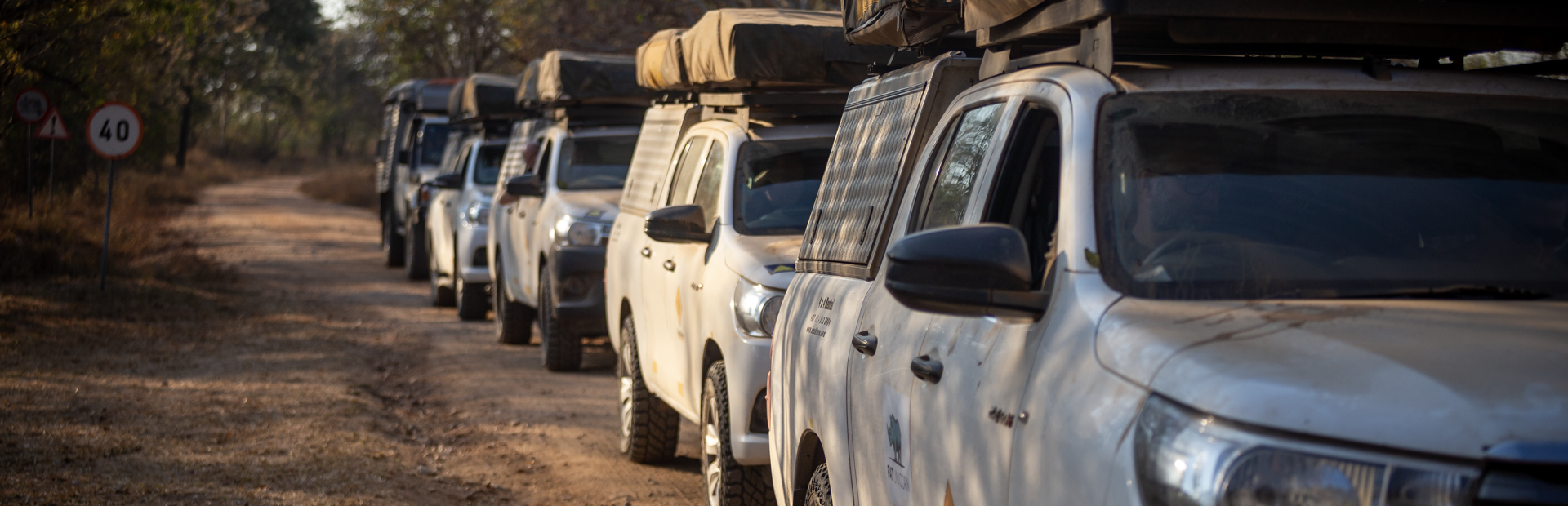 a row of hilux trucks are parked on a dirt road