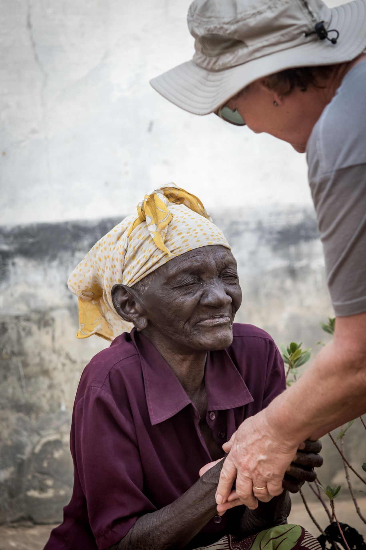 a woman in a hat holds the hand of an older woman
