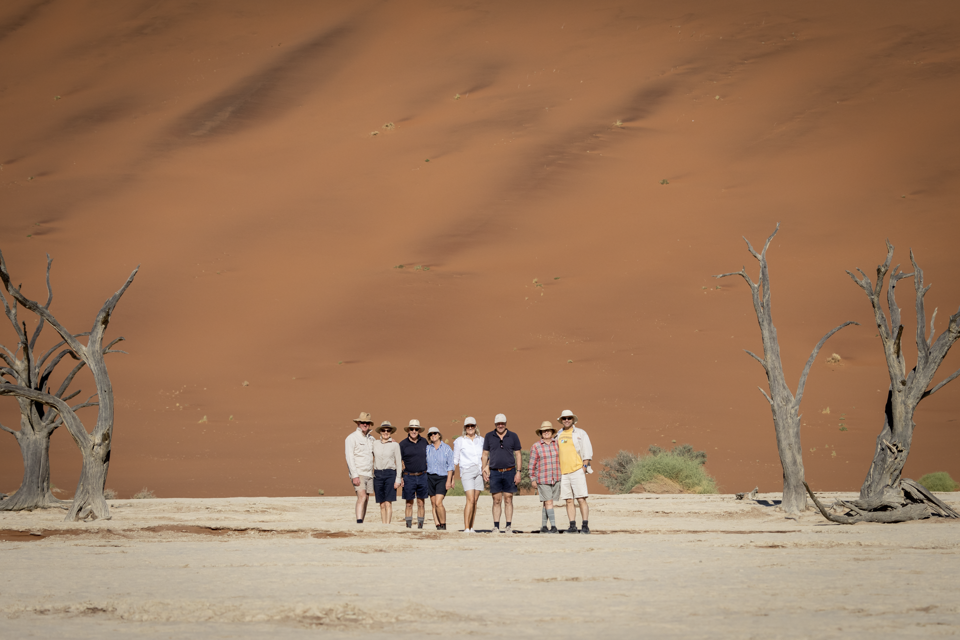 a group of people standing in front of a sand dune
