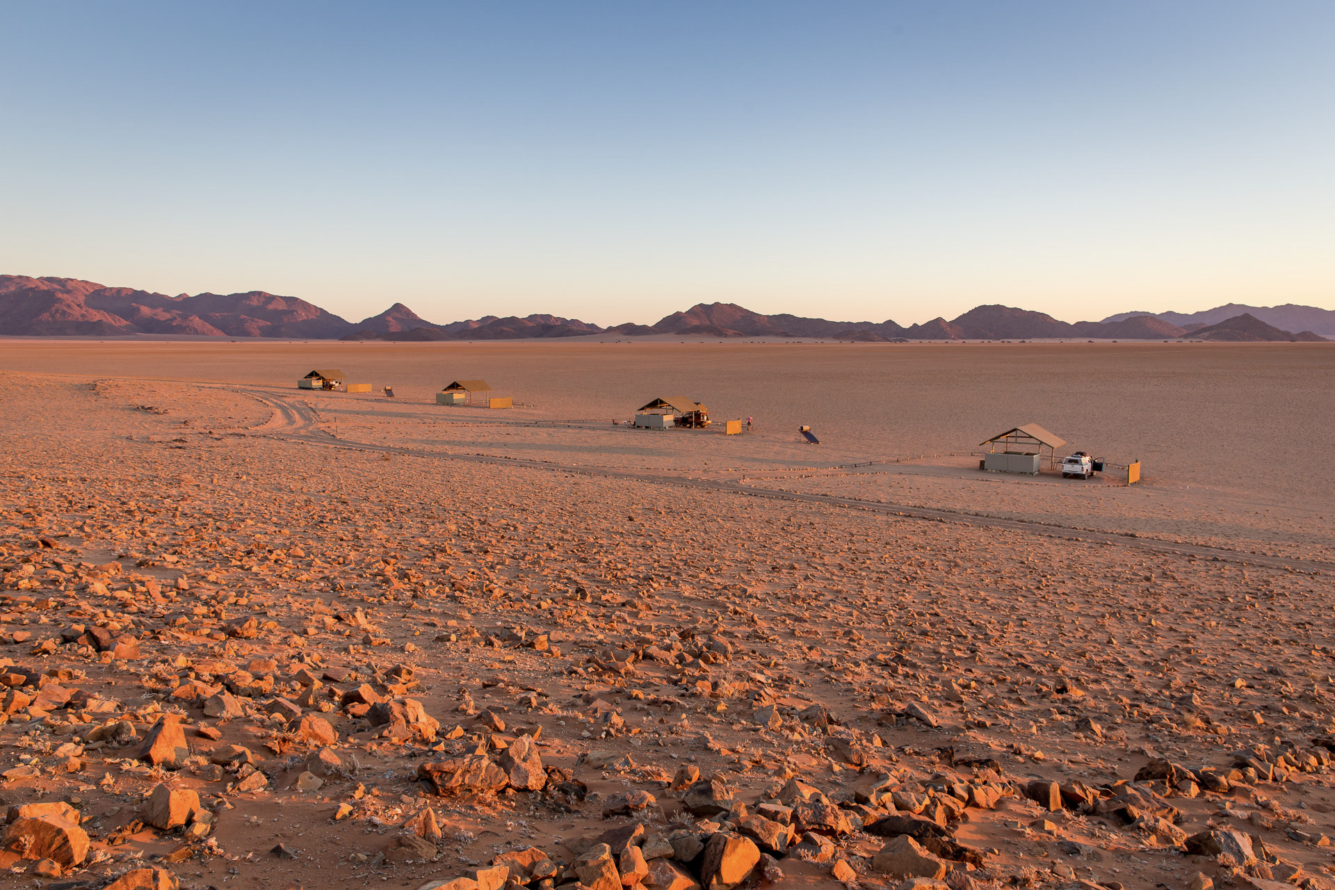 a row of tents in the desert with mountains in the background