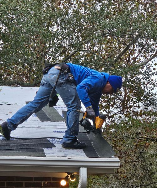 A man in a blue jacket is working on a roof.