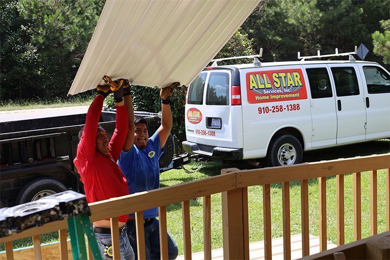 Two men are carrying a piece of metal in front of an all star van.