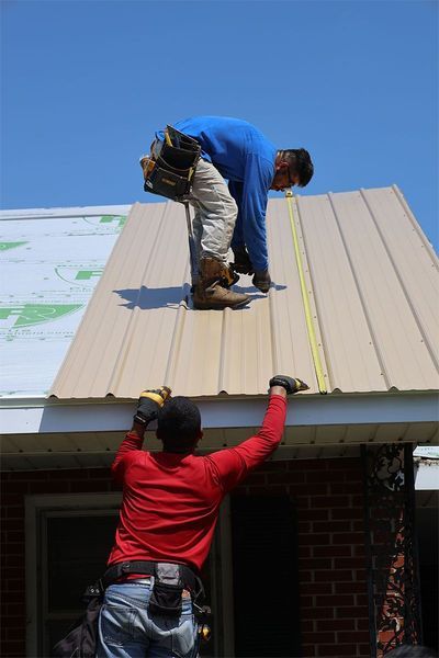 Two men are working on the roof of a house.
