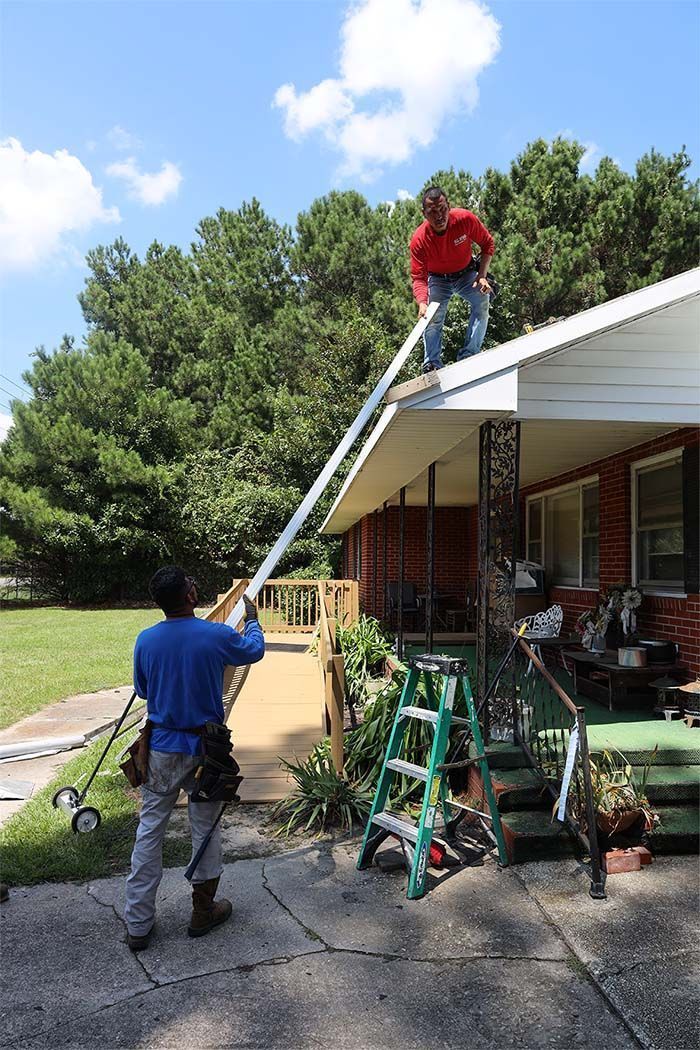 A man is standing on a ladder on the roof of a house.