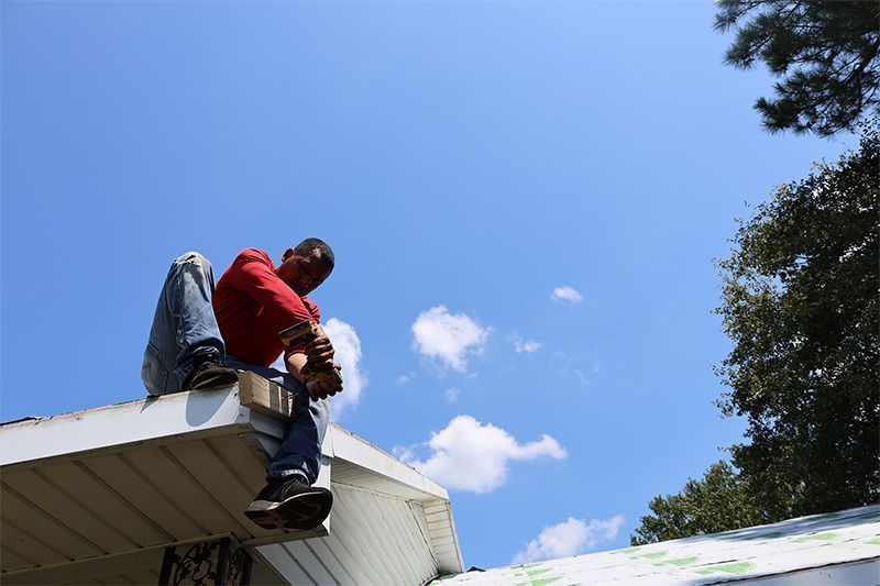 A man is sitting on the roof of a house.