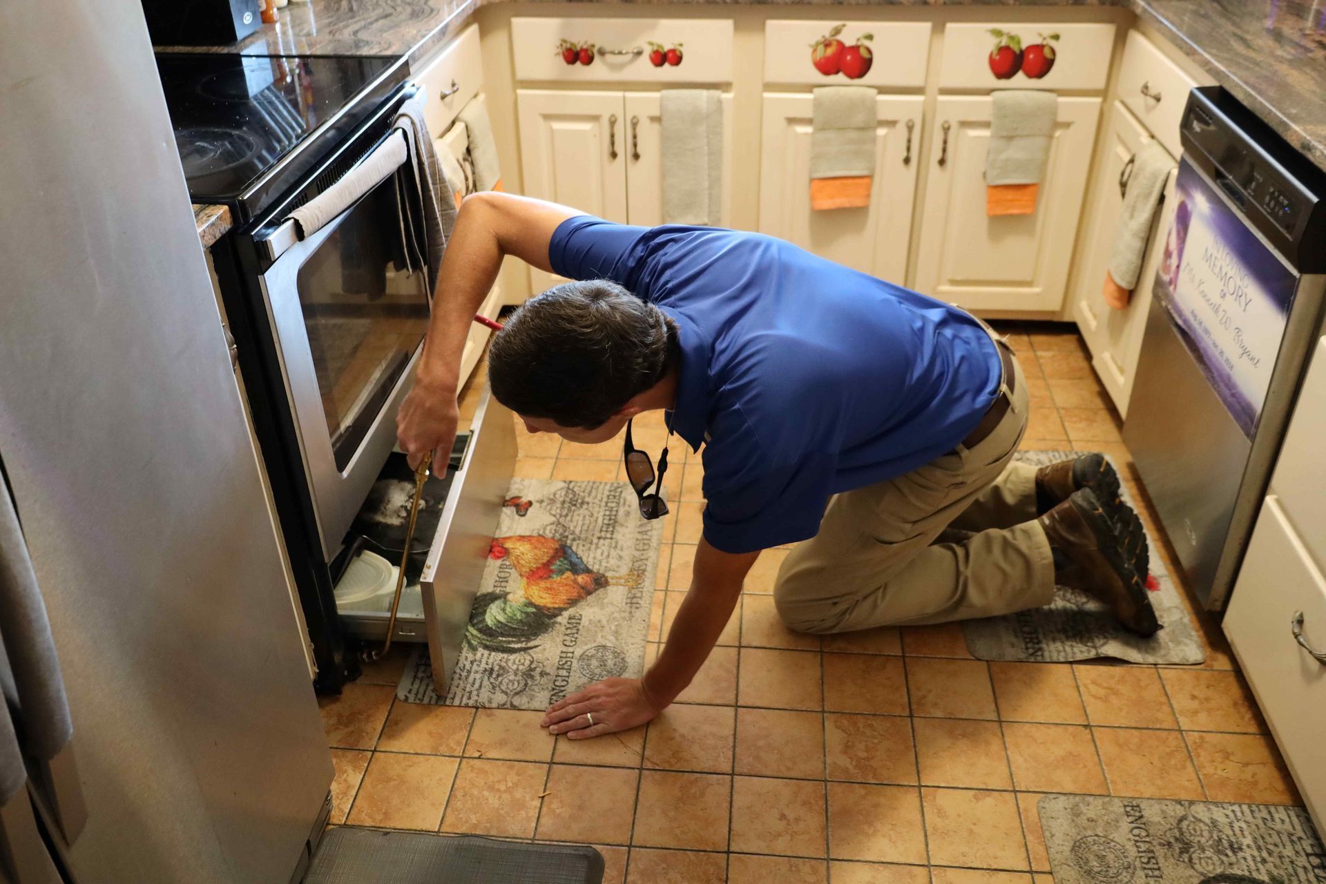 A man is kneeling down in a kitchen looking into a drawer.