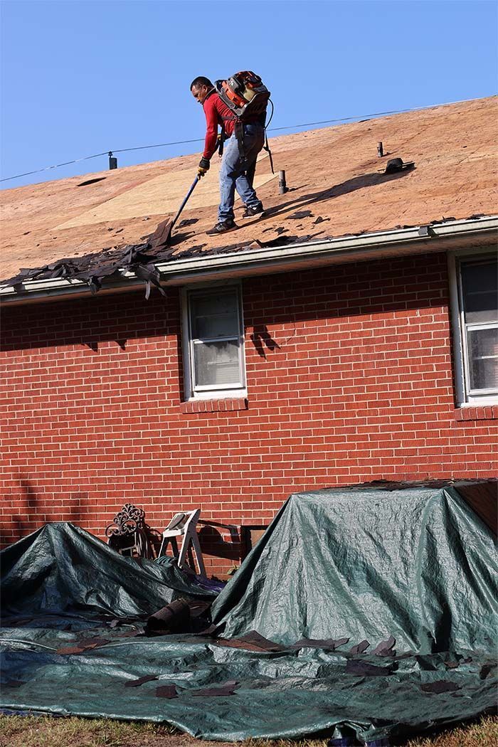 A man is working on the roof of a brick house.