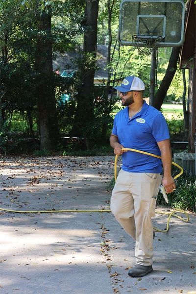 A man is standing in front of a basketball hoop holding a hose.