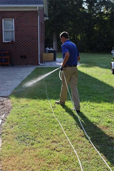 A man is spraying a lawn with a hose.