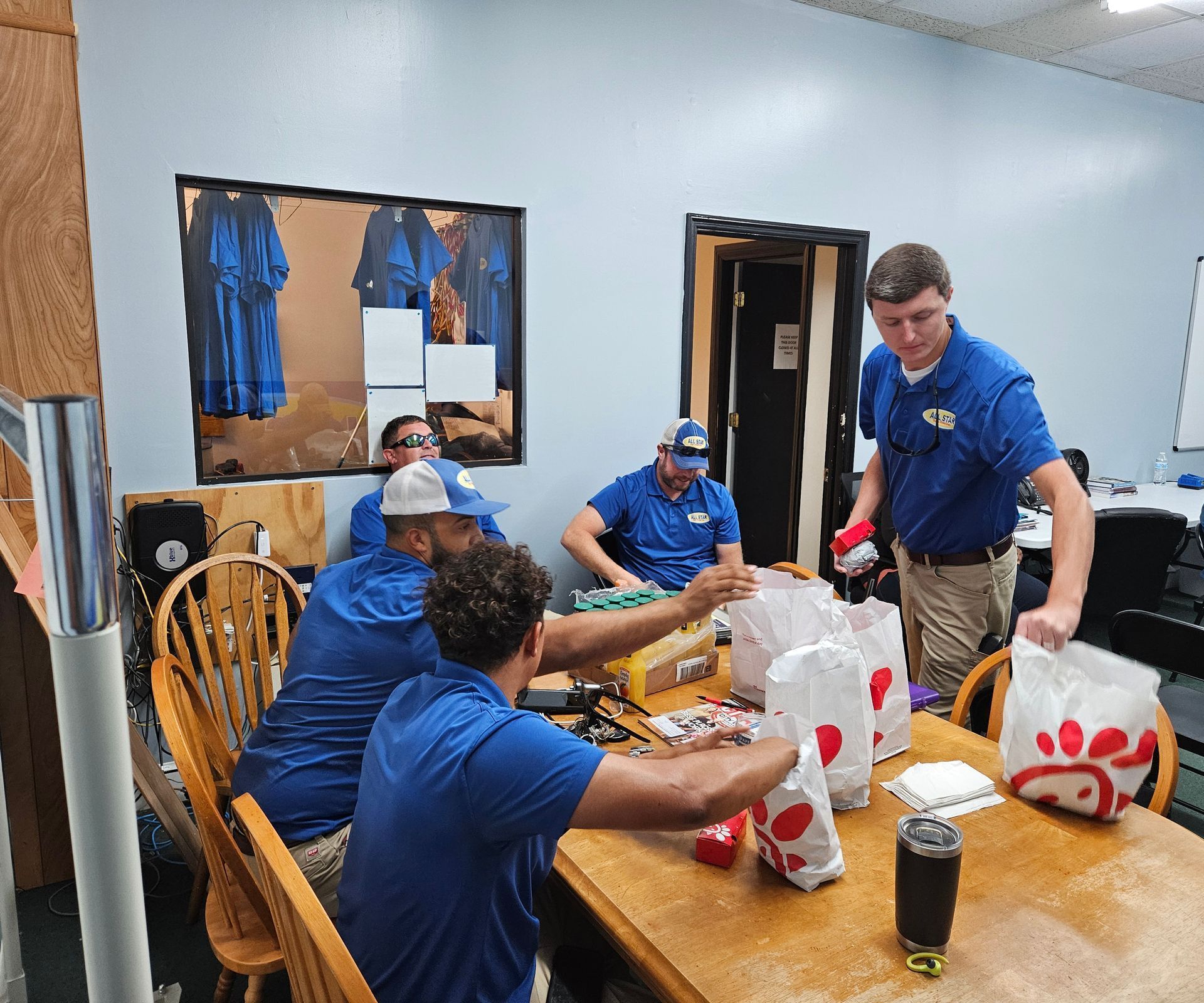 A group of men are sitting at a table with bags of chicken nuggets.