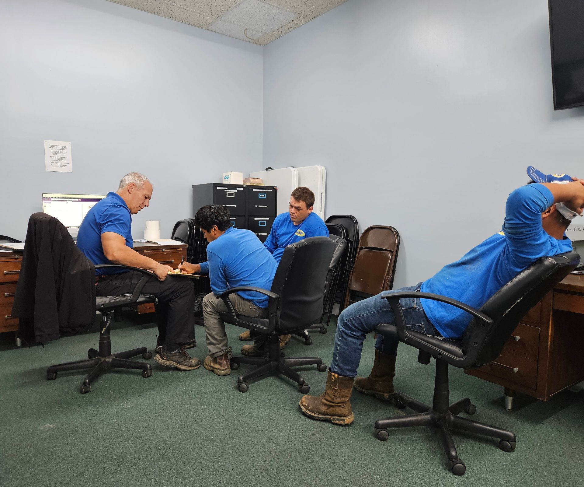 A group of people in blue shirts are sitting around a table