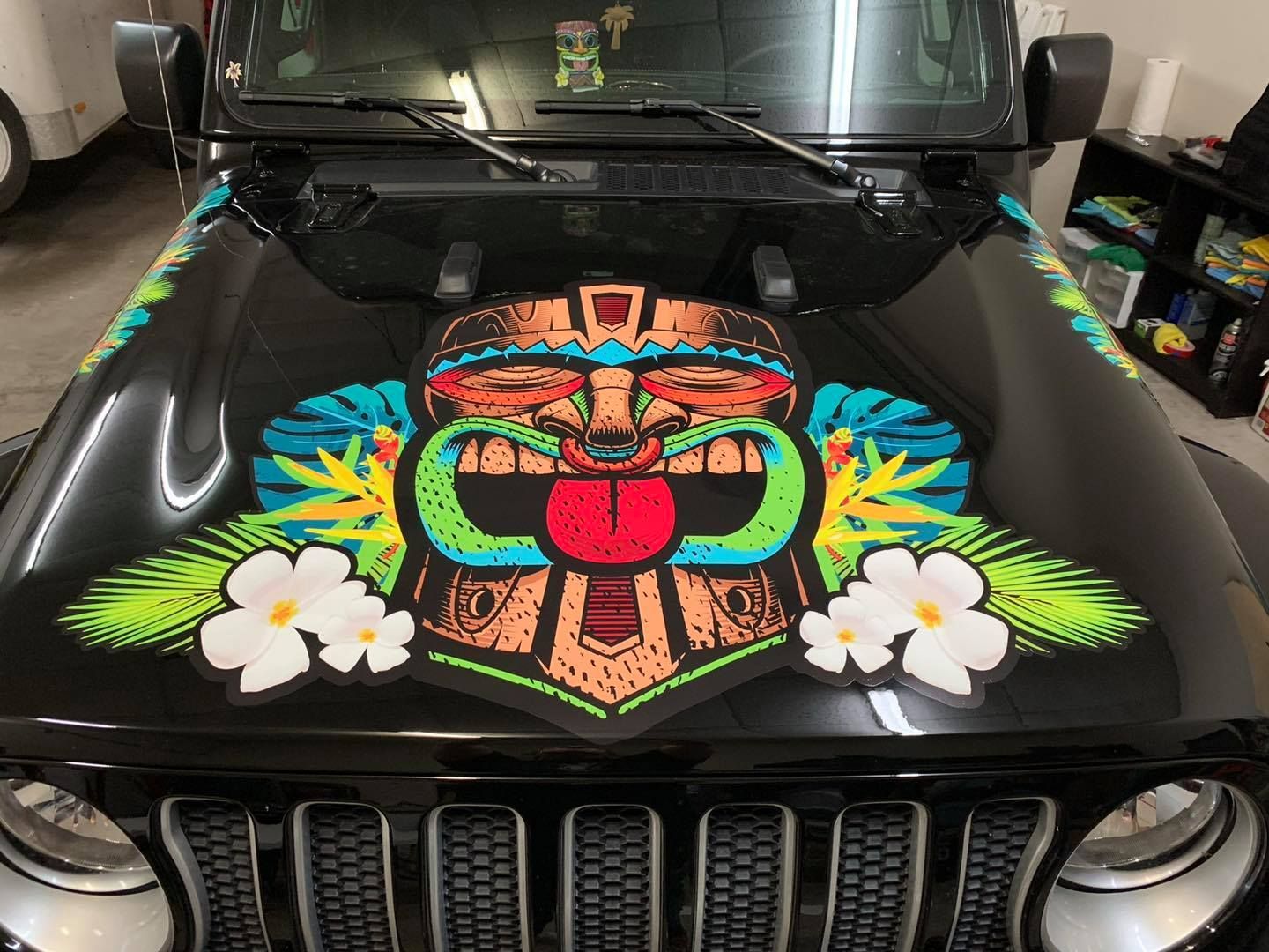 Black Jeep hood with colorful tiki graphic and tropical leaves and flowers.