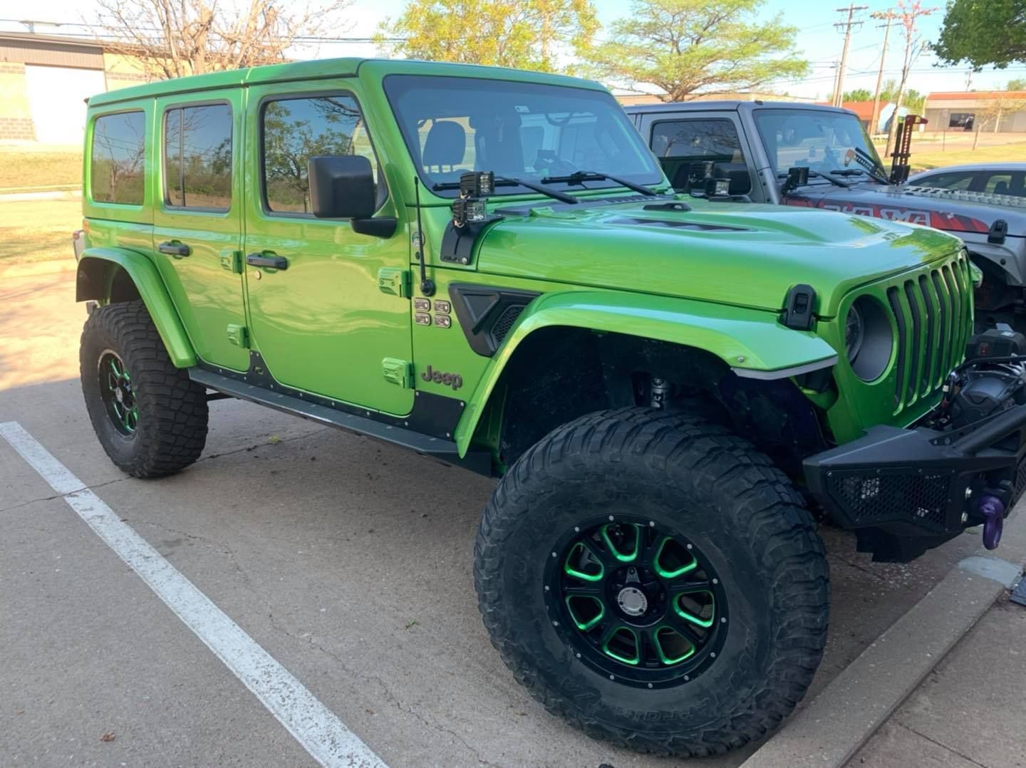 Bright green Jeep Wrangler with large tires parked outside.