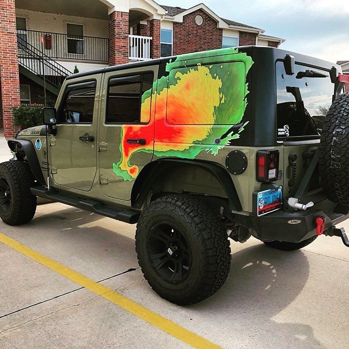 Green Jeep with a colorful weather radar wrap on its side.