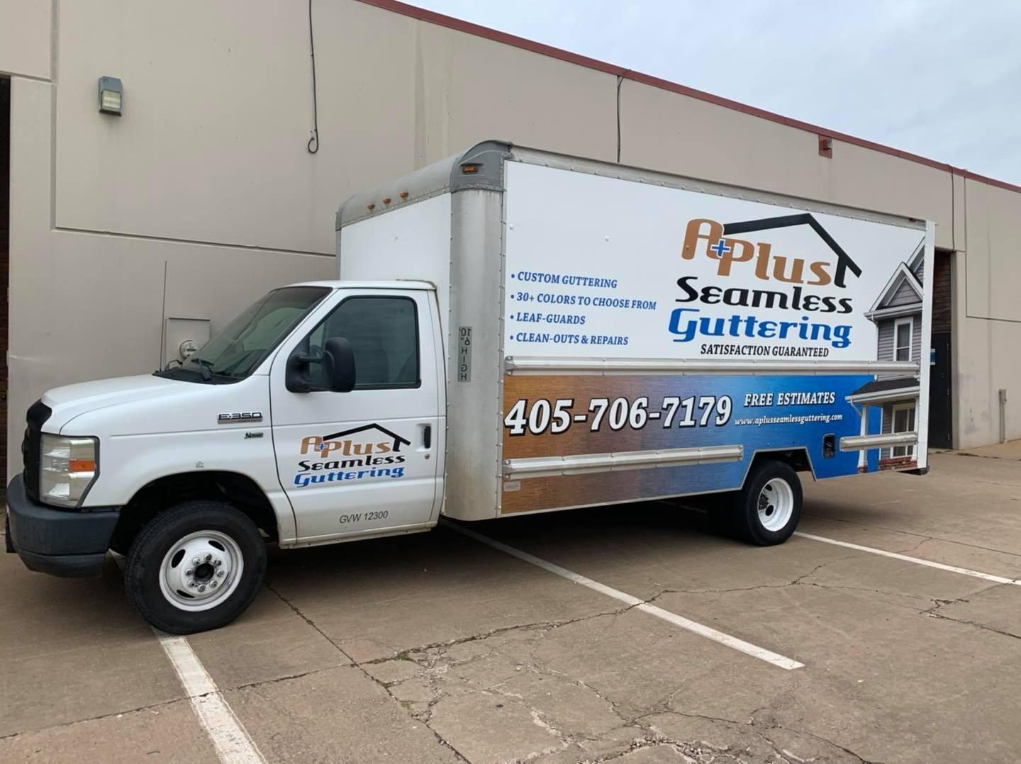 White box truck with A Plus Seamless Guttering logo parked outside a building; phone number visible.