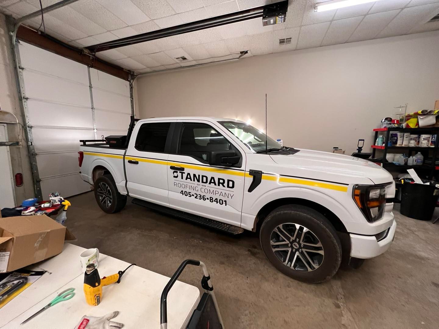 White pickup truck with yellow stripes parked inside a garage.  "Standard" logo on the side.