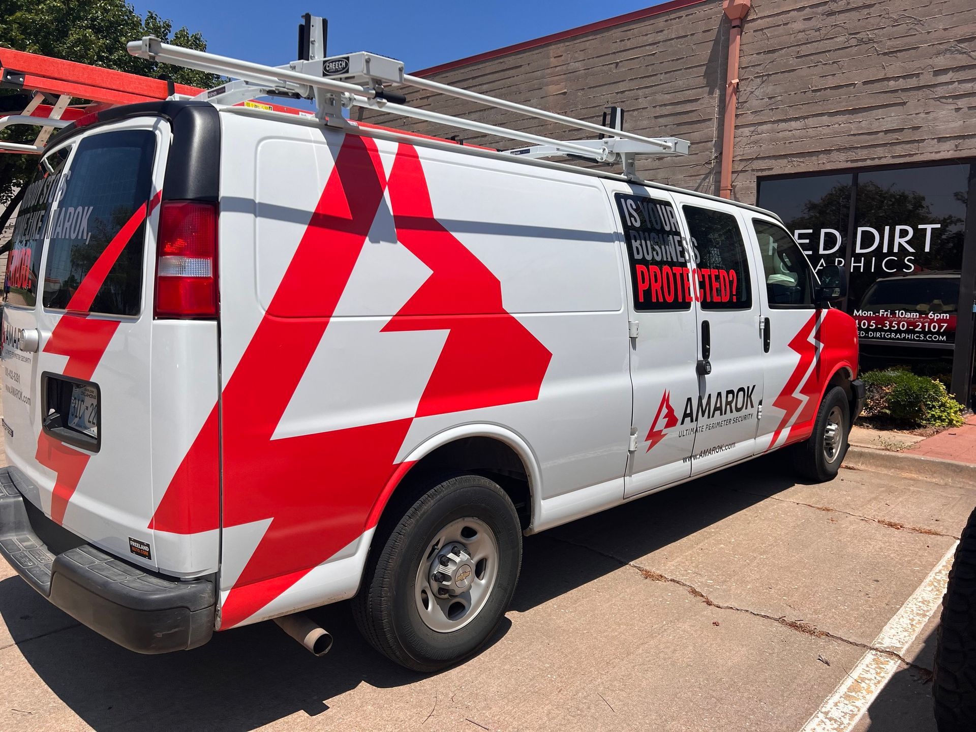 White van with red lightning bolt graphics parked outside a building. The van has a roof rack.