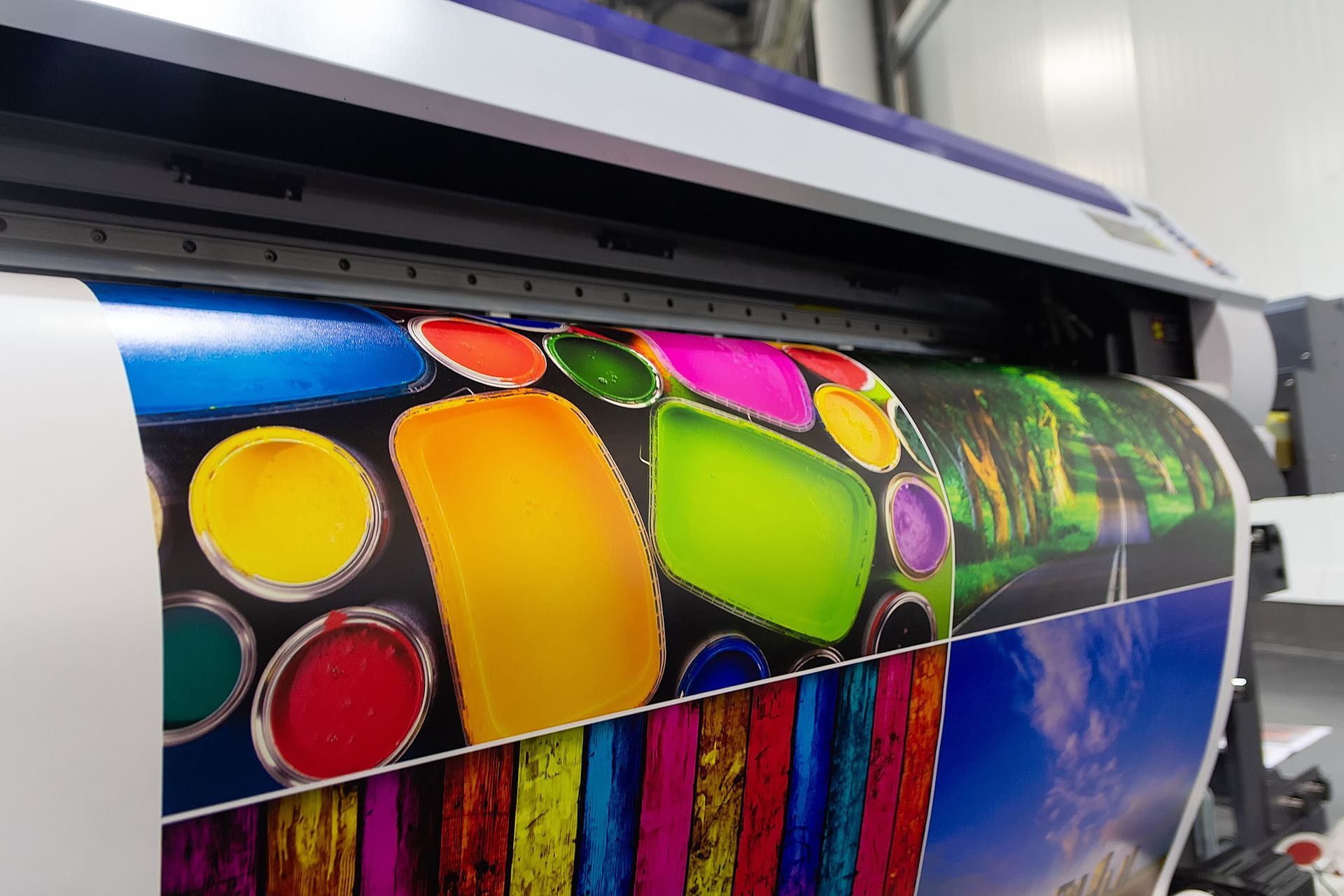 Large format printer printing colorful art on a roll of paper.
